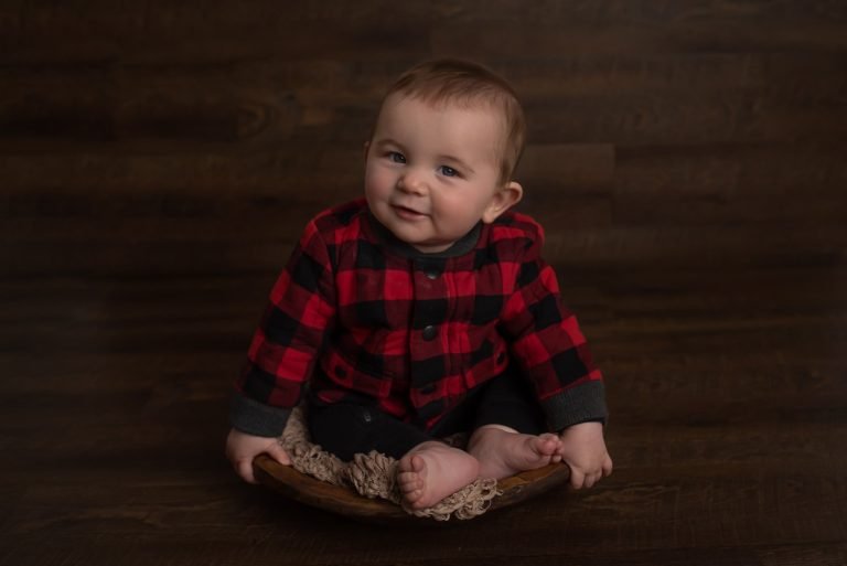 Milestone Photoshoot - Baby in plaid shirt smiling at the camera