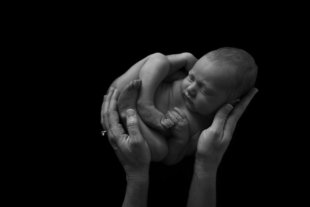 moms hands holding a sleeping newborn