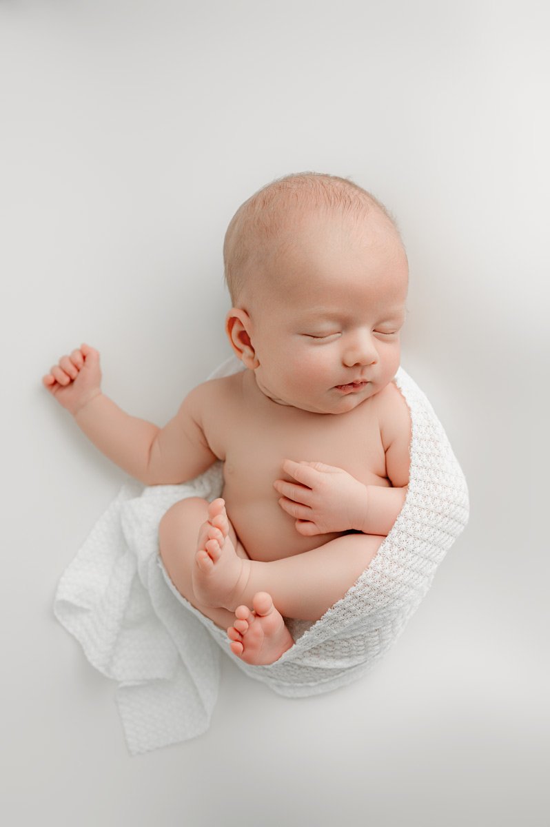 Newborn baby sleeping on a soft white blanket, natural newborn portrait for West Vancouver families