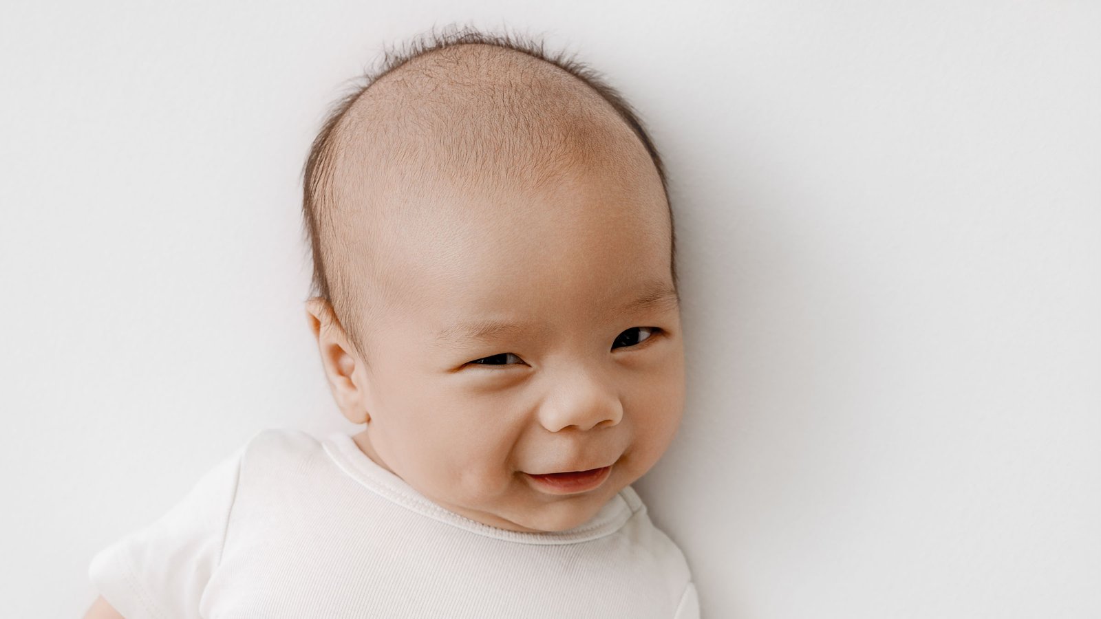 A baby looking at the camera with a slight smile.